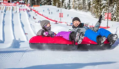 Fröhliche Familie beim Rodeln auf einer verschneiten Rodelbahn