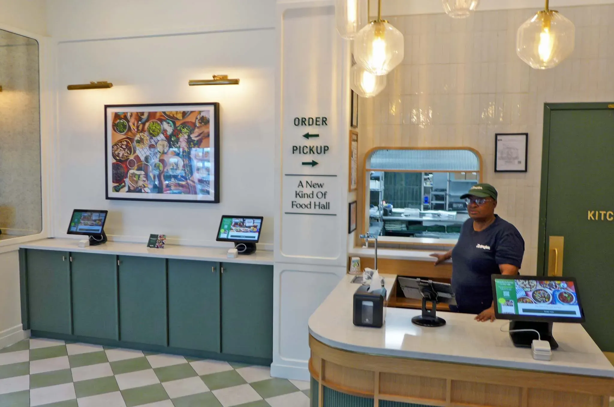 Frau hinter Theke mit Küche im Hintergrund.