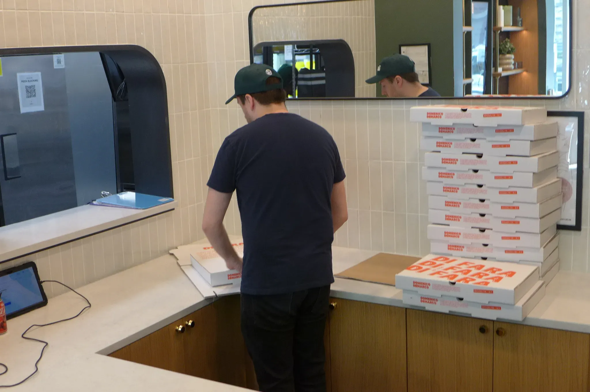 Mann faltet Kartons mit dem Rücken zur Kamera.