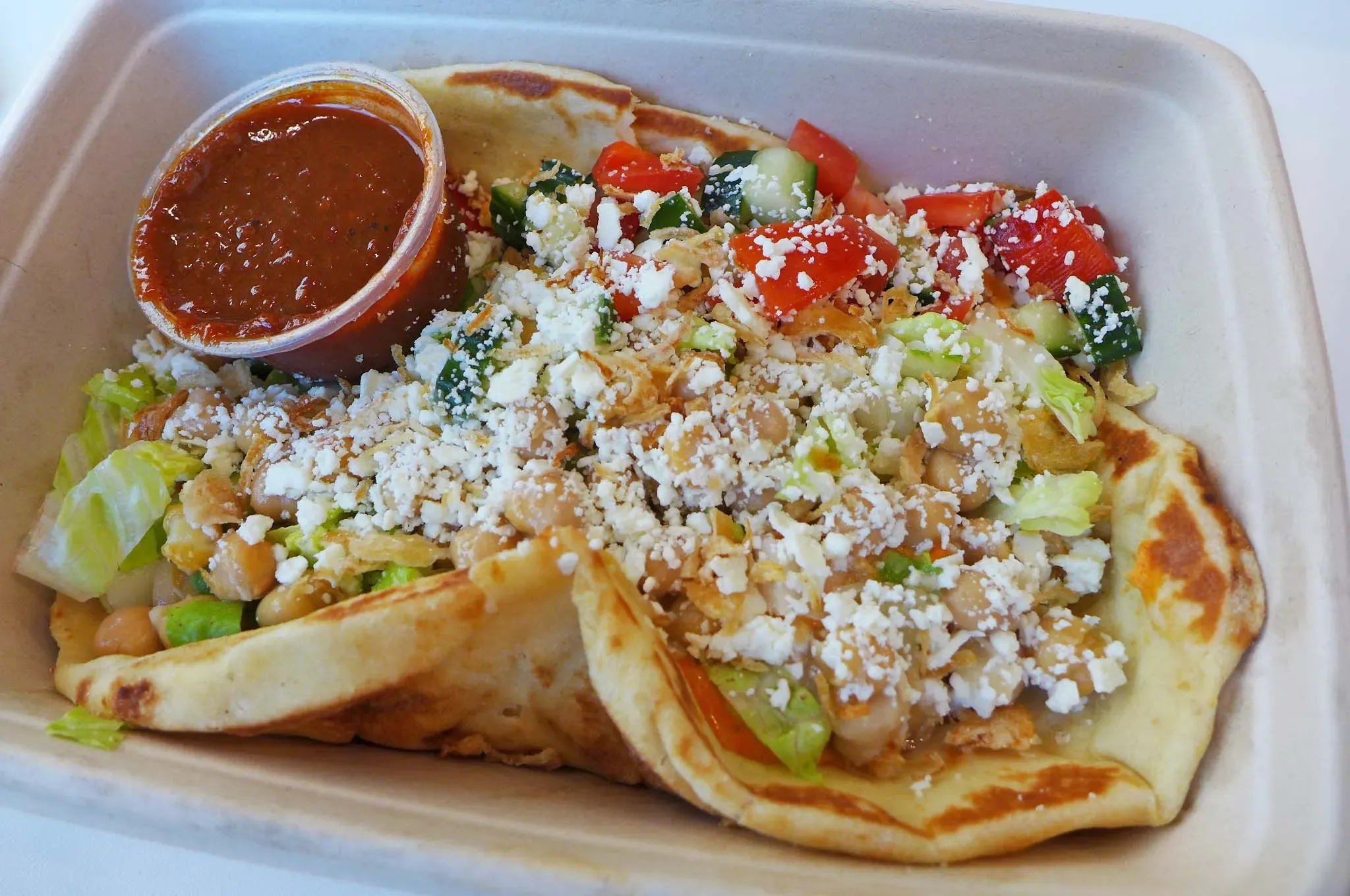 Pitabrot mit Gemüse in Behälter gequetscht.