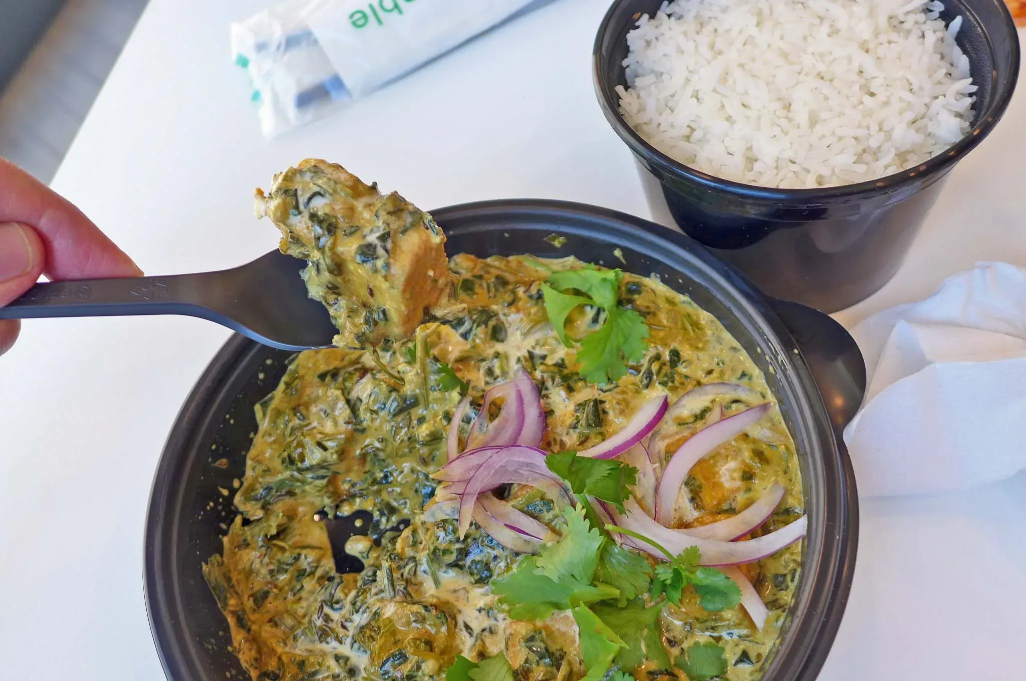 Runder Plastikbehälter mit spinatiger Suppe.