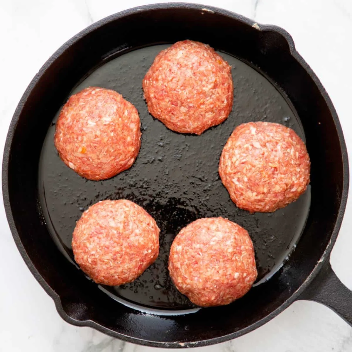 Ungebackene geformte Frikkadels in der Pfanne.