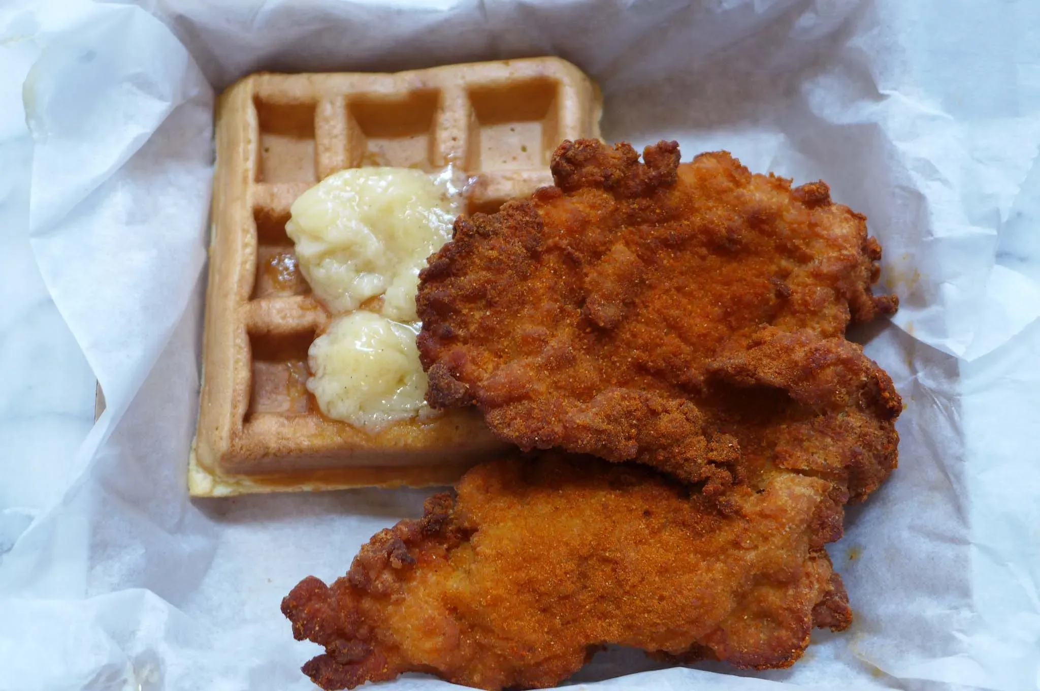 Zwei Schnitzel und kleine Waffel mit Butter.