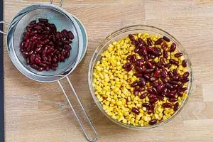 Abgetropfter Mais und Kidneybohnen werden als weitere Schichten für den mexikanischen Taco Salat hinzugefügt.