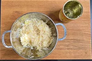 Abgetropftes Sauerkraut in einem Küchensieb unter fließendem Wasser abspülen, um überschüssiges Salz zu entfernen