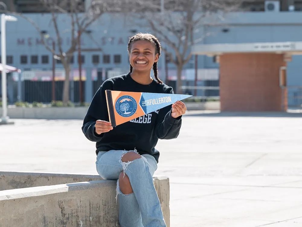 Absolventin hält ein Universitätsbanner als Symbol für Weiterbildung.