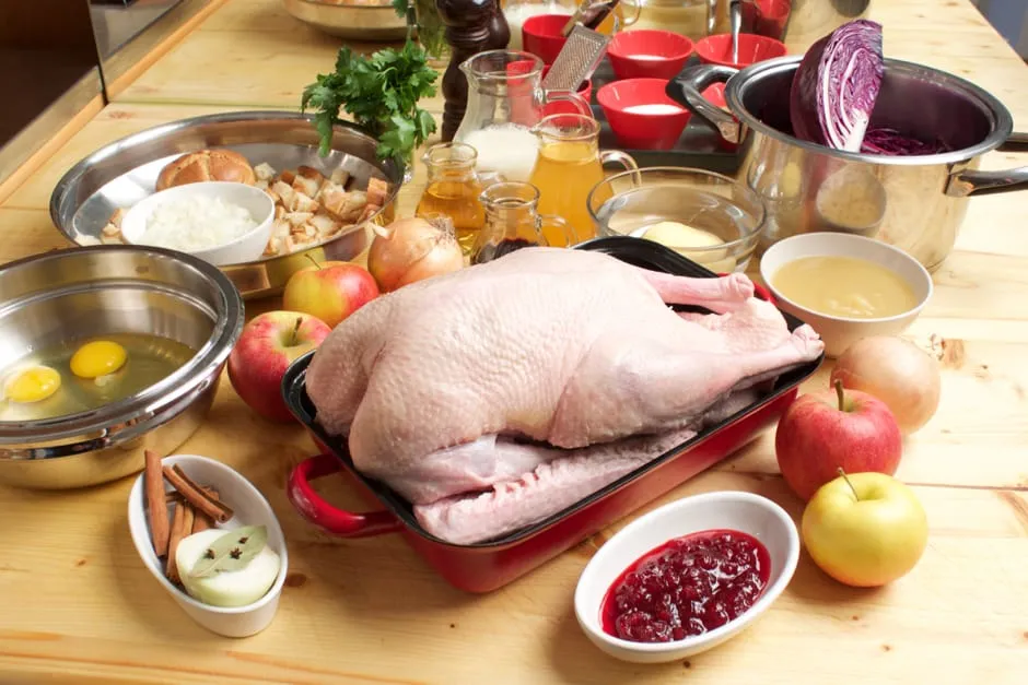 Alle vorbereiteten Zutaten für den Gänsebraten, Soße und Beilagen übersichtlich auf einer Arbeitsfläche.