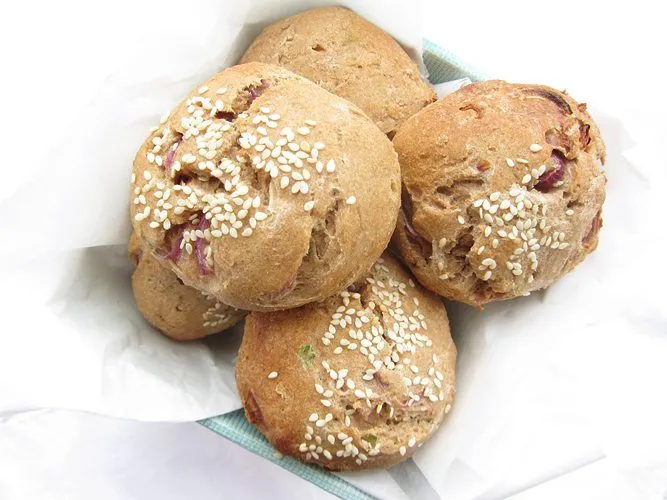 Alt text: Frisch gebackene Dinkel-Buchweizen-Brötchen auf einem Holzbrett, leicht bestäubt mit Mehl.