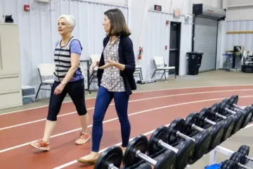 Ältere erwachsene Frau geht auf einer Indoor-Laufbahn und trägt die in der Studie verwendete Weste.