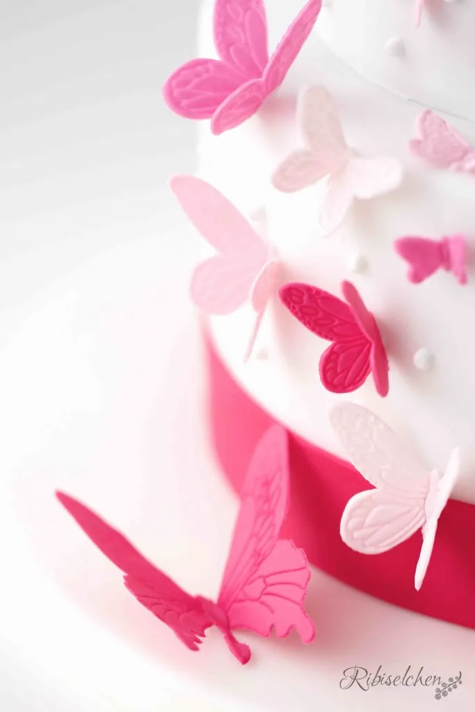 Anmutige Fondant-Schmetterlinge, sorgfältig auf der Tauftorte befestigt, verleihen der Torte eine lebendige Note