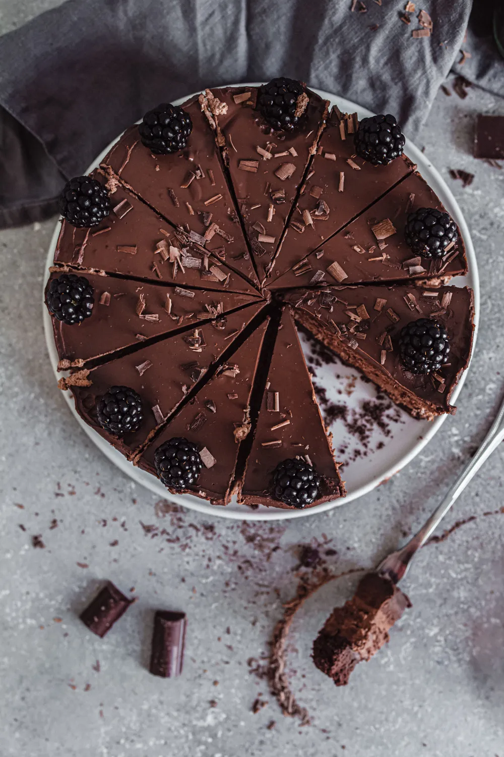 Anschnitt der veganen Schoko Sahne Torte, deutlich sichtbar sind die vier köstlichen Schichten aus Biskuit, Mousse und Ganache