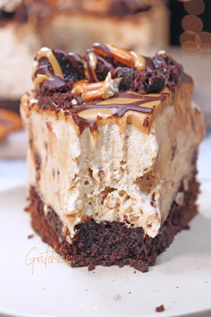 Anschnitt einer selbstgemachten veganen Erdnussbutter-Mousse-Torte, die an Ben &amp; Jerry's erinnert, mit Brownie-Boden und knusprigen Brezelstücken.