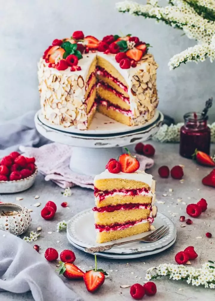 Anschnitt einer veganen Himbeer-Sahnetorte, die ihre saftigen Schichten enthüllt.