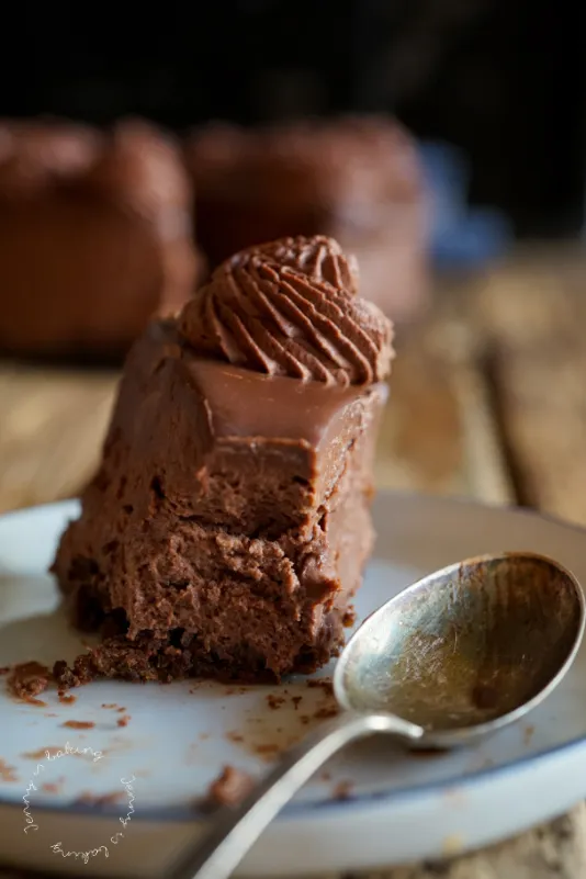 Anschnitt eines opulenten Schoko-Käsekuchens ohne Backen, mit deutlich sichtbaren Schichten von Boden, Füllung und Ganache