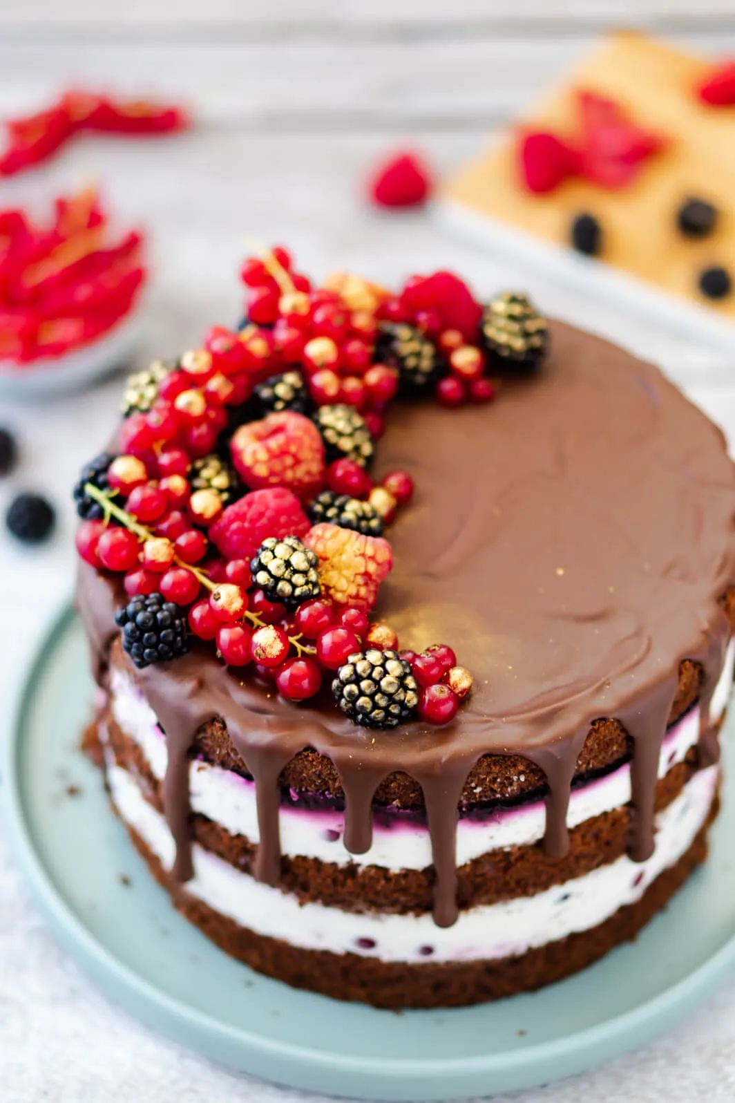 Ansicht einer fertig dekorierten mehrstöckigen Beerentorte mit einem appetitlichen Schoko-Drip an den Seiten.