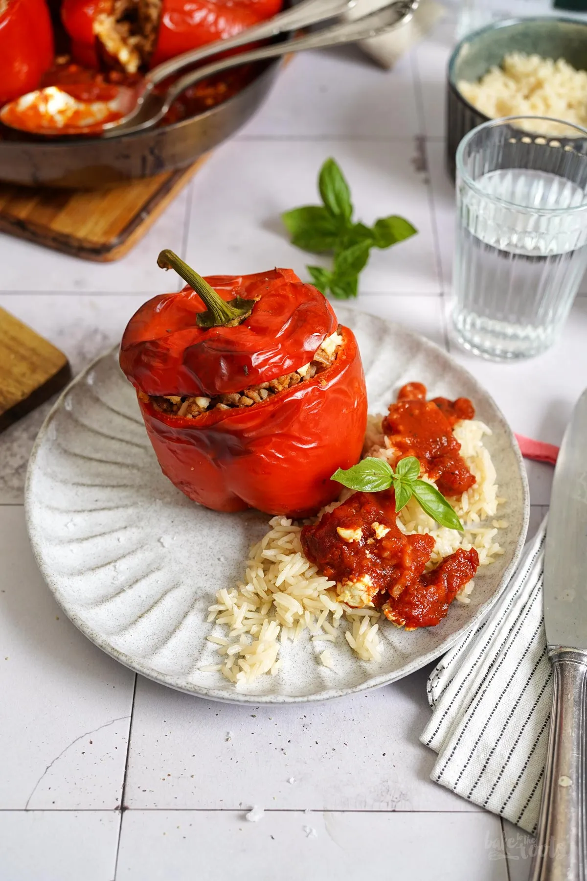 Ansicht von oben auf eine Pfanne mit bunten, gefüllten Paprika, die mit Kräutern garniert sind