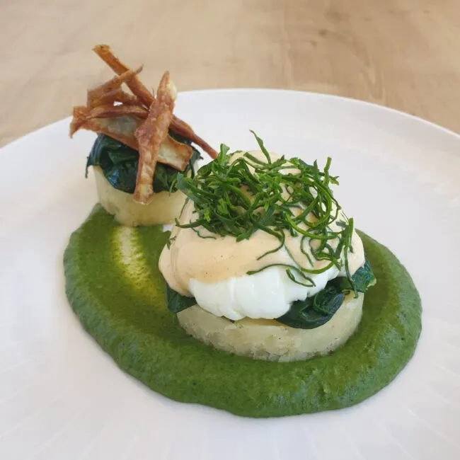 Ansprechend angerichtetes pochiertes Ei auf cremigem Spinat und Kartoffelstampf für das Ostermenü.