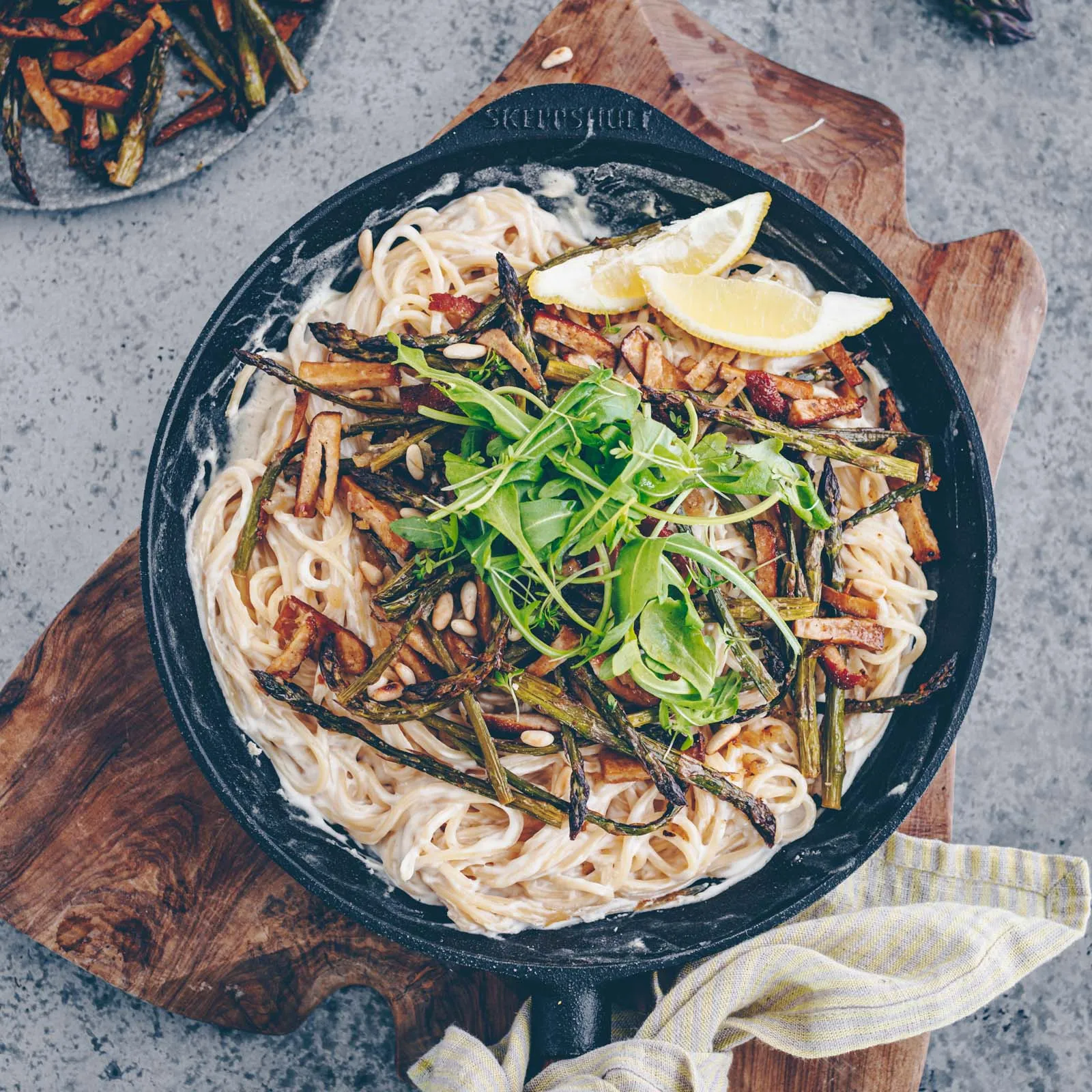 Ansprechende Präsentation einer veganen Spargel-Tofu-Pasta mit Rucola und Pinienkernen