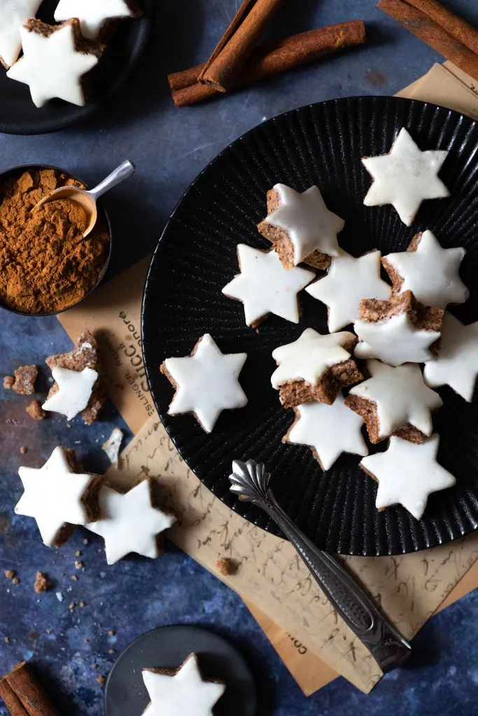 Ansprechende Präsentation von Zimtsternen mit weißer Zuckergussglasur, kunstvoll auf einem Plätzchenteller arrangiert