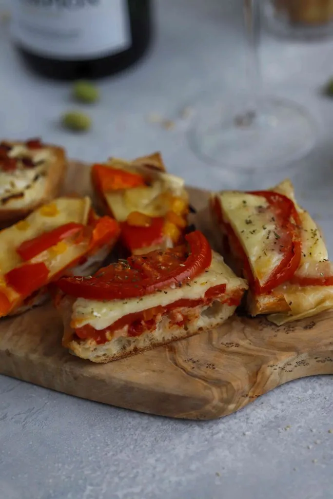 Apéro-Baguettes mit Käse und Tomaten auf einem Holzbrett angerichtet
