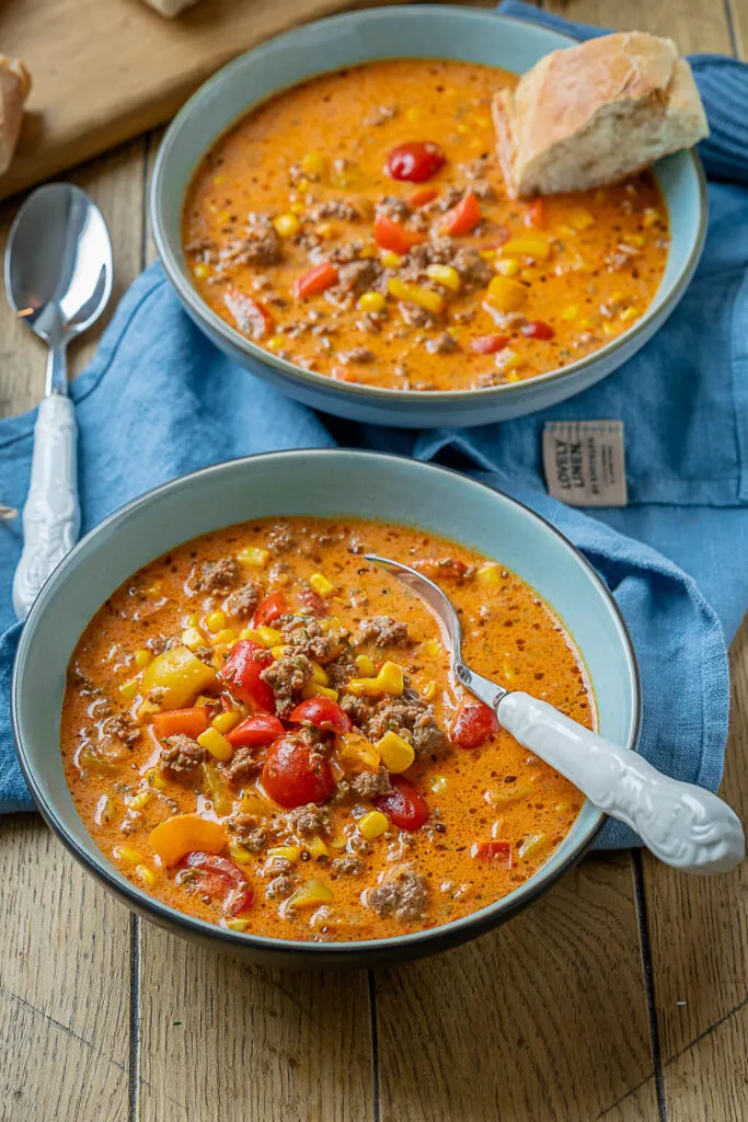 Appetitlich angerichtete Pizzasuppe mit Hackfleisch, Mais und Paprika, gekrönt mit Petersilie und Käse.