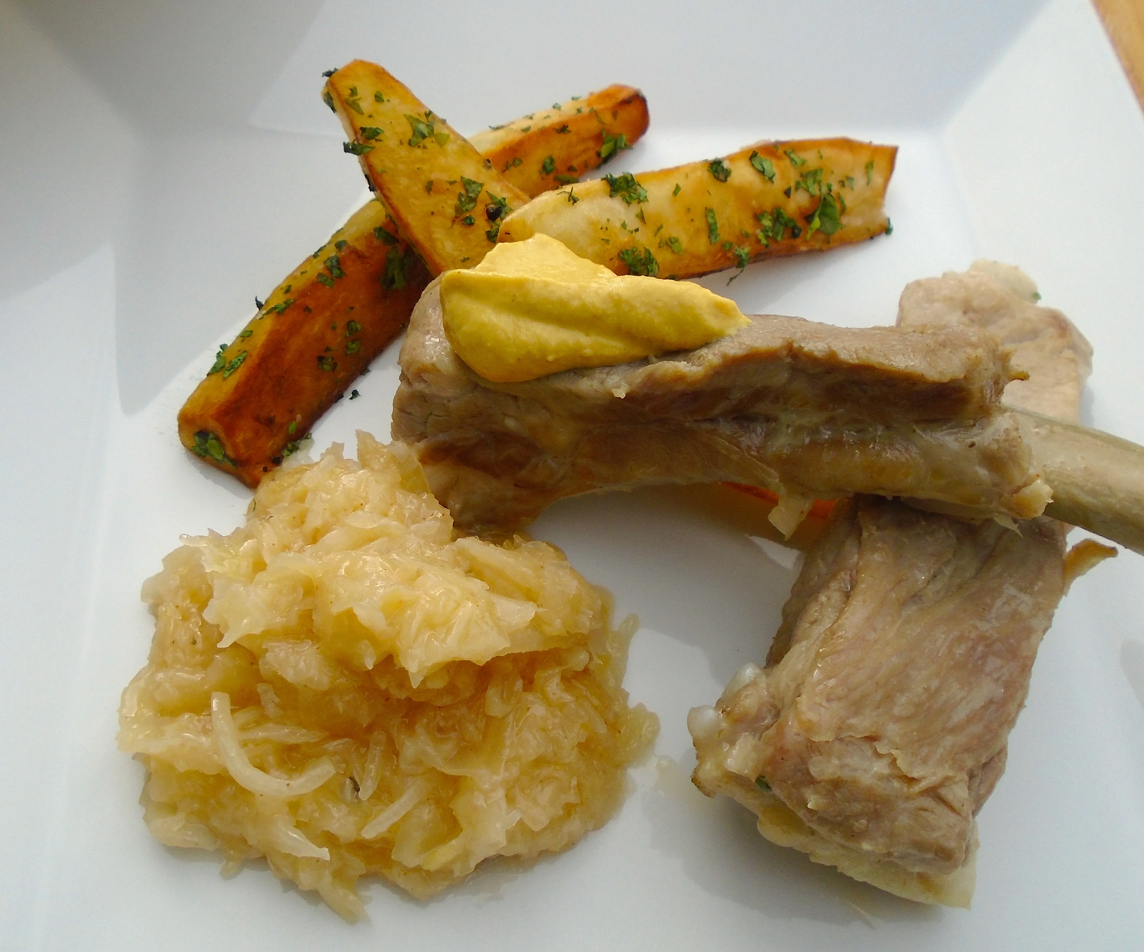 Appetitlich angerichtete Schälrippchen mit Sauerkraut und knusprigen Bratkartoffeln
