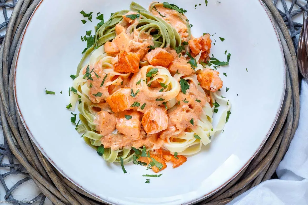 Appetitliche Lachswürfel und Tagliatelle in einer cremigen Tomaten-Sahne-Soße, bereit zum Servieren.