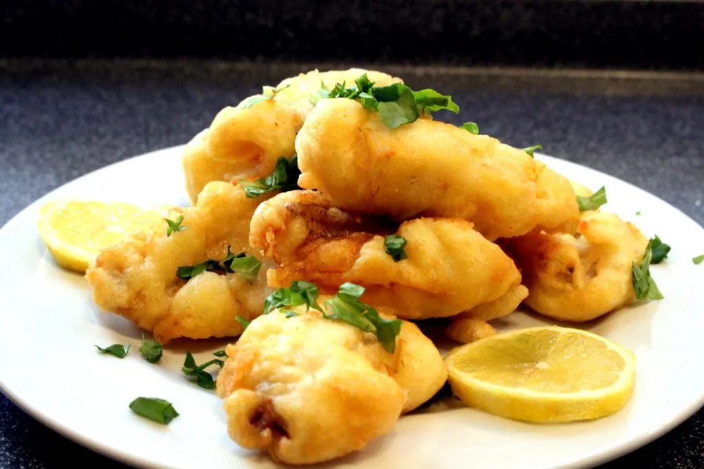 Appetitliche Präsentation von Egli Filets im Bierteig mit goldbrauner Kruste, begleitet von Spargel