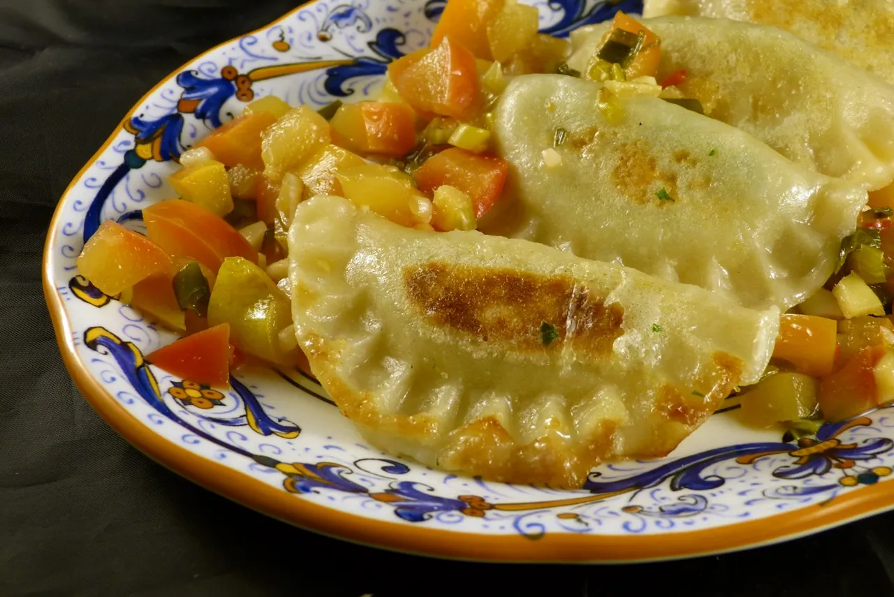 Appetitliche Teigtaschen gefüllt mit Kohlrabistielen und Tofu, serviert mit Apfelsauce, ein köstliches Beispiel für Essen mit Gemüse ohne Verschwendung.