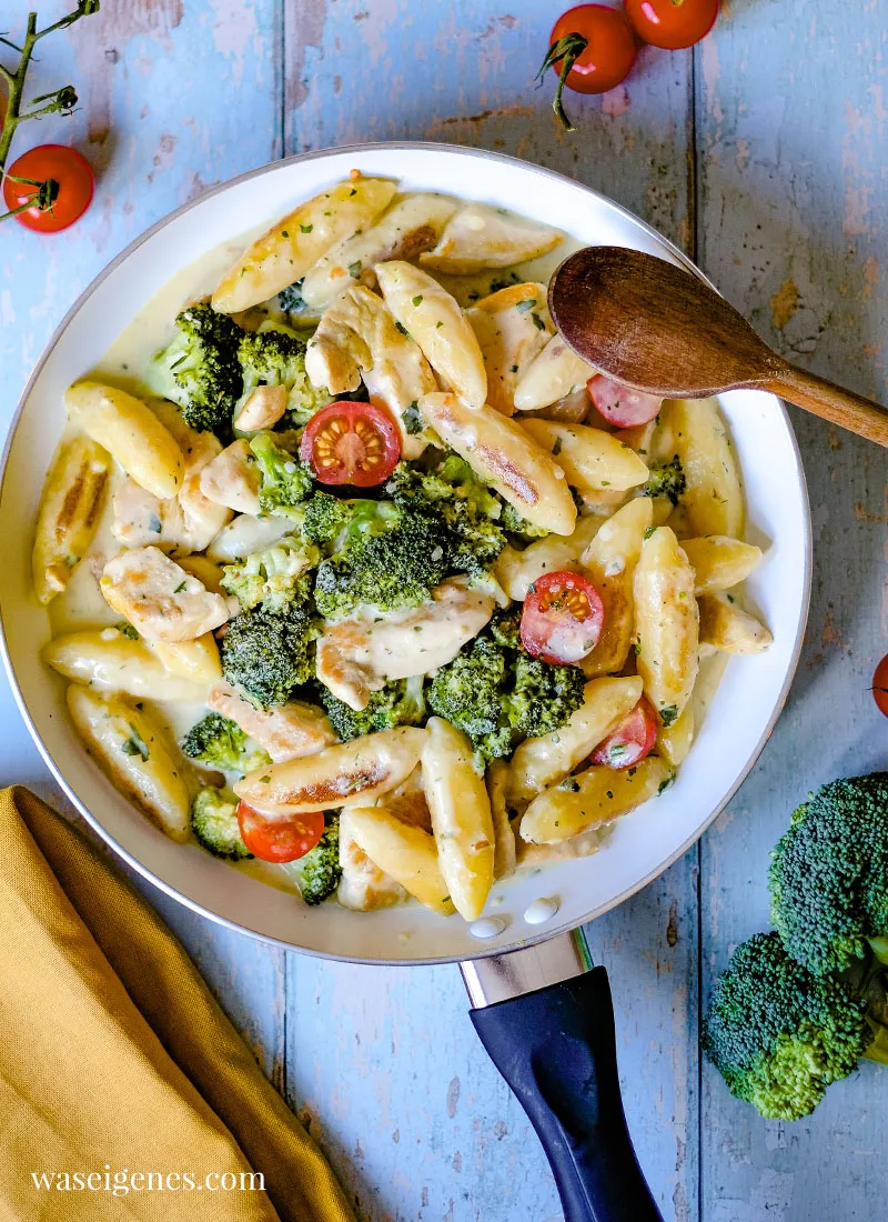 Appetitlicher Bissen einer cremigen Schupfnudelpfanne mit Hähnchen, Brokkoli und Tomaten auf einer Gabel