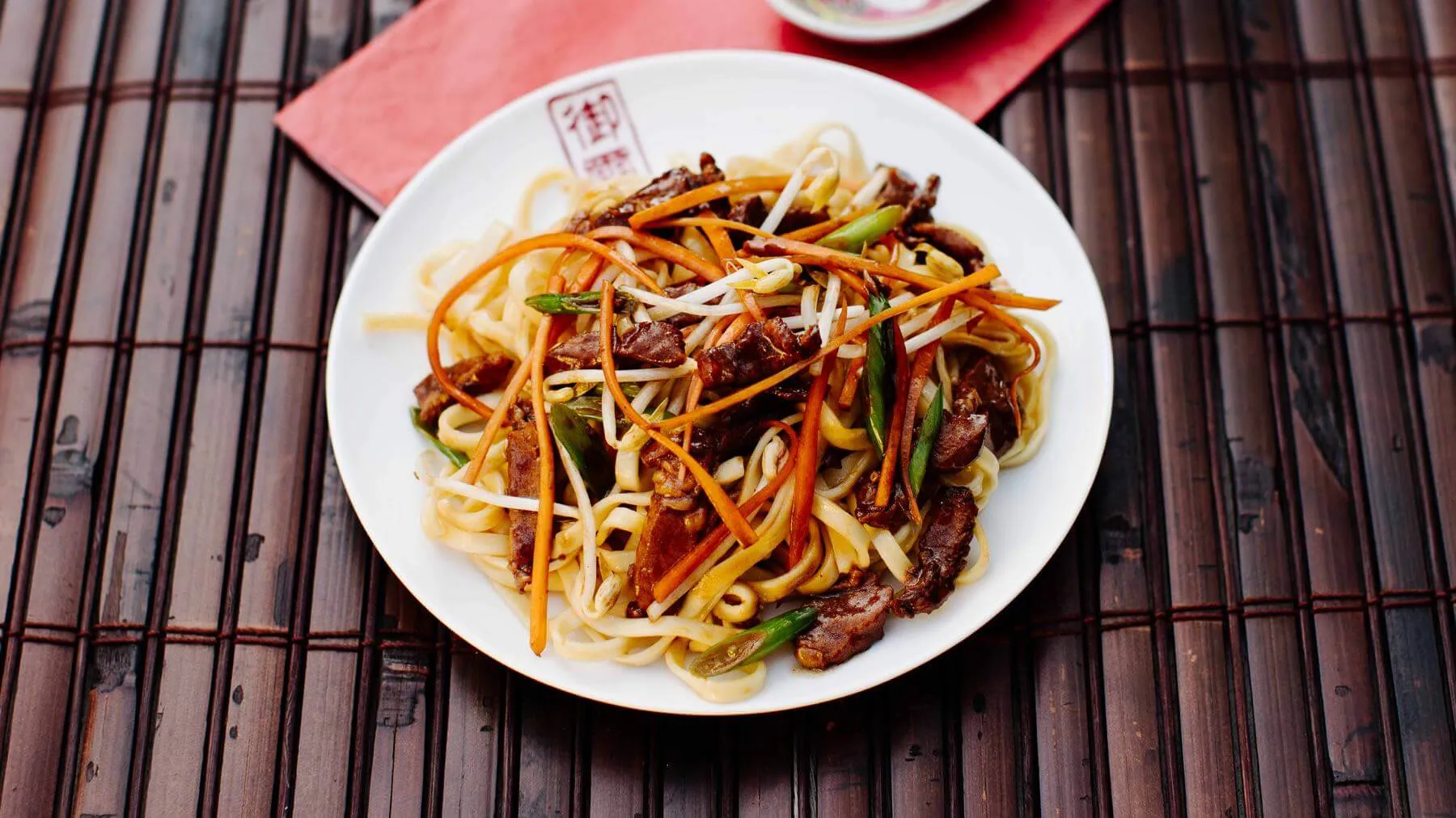 Aromatische gebratene Nudeln mit zartem Schweinefleisch und frischem Gemüse, schnell zubereitet im Wok, ein beliebtes chinesisches Rezept