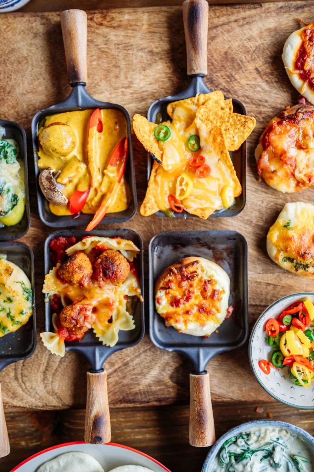 Arrangement von vorgebackenen Mini-Pizzateigen und hausgemachten Saucen für das Raclette