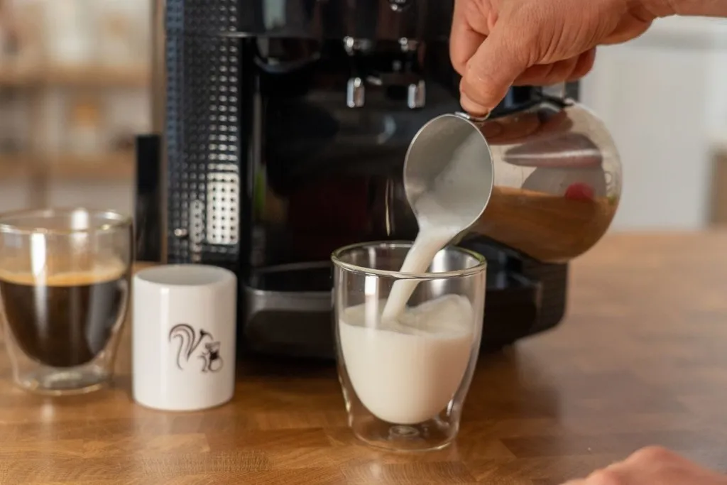 Aufgeschäumte Milch wird aus dem Krups in eine Tasse gegossen