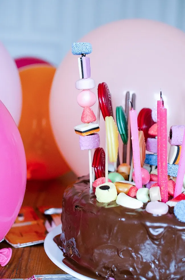 Aufgetragene Zartbitter-Kuvertüre auf dem Kuchenboden, die einen glänzenden Untergrund für die Süßigkeiten bildet.