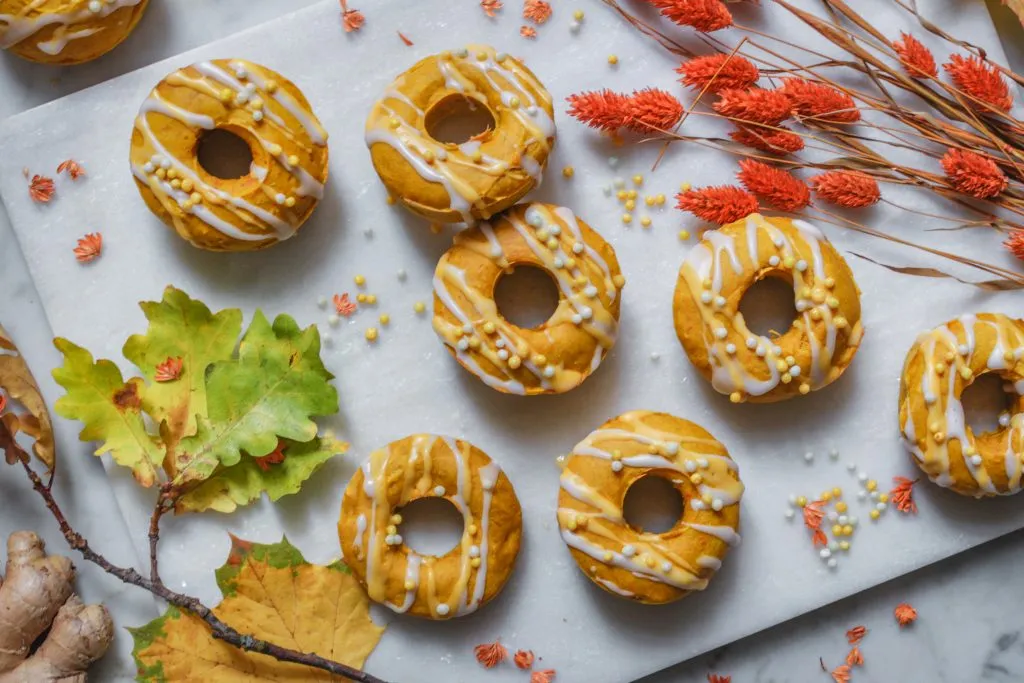 Auswahl an veganen Kürbis-Donuts: bestreut mit Zimtzucker und überzogen mit leuchtender Zitronenglasur