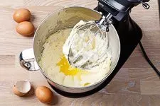 Backschritt 3: Eine Küchenmaschine rührt Eier einzeln in eine helle, cremige Butter-Zucker-Mischung für den Marmorkuchenteig.