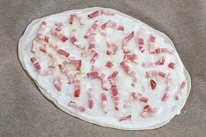Belegen vom Flammkuchen mit Speck und Zwiebeln