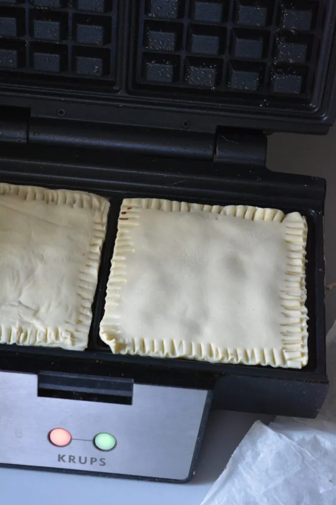 Blätterteigwaffeln im heißen Waffeleisen, während sie goldbraun und knusprig backen