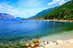 Blick auf den Gardasee in Italien mit Bergen im Hintergrund, ein beliebtes Ziel für Familienurlaub im Juli.