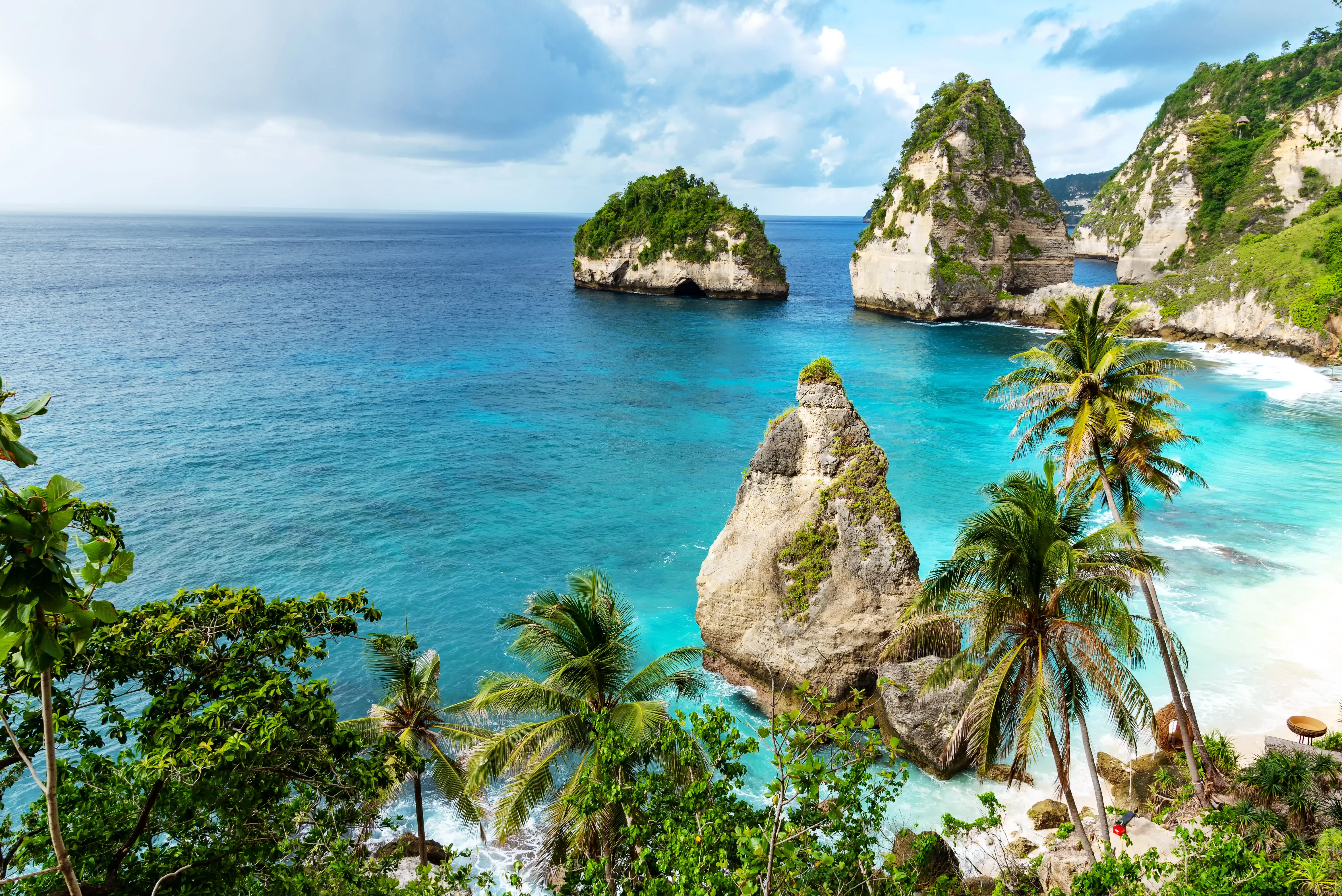 Blick auf einen tropischen Strand auf Bali mit Palmen und türkisfarbenem Wasser