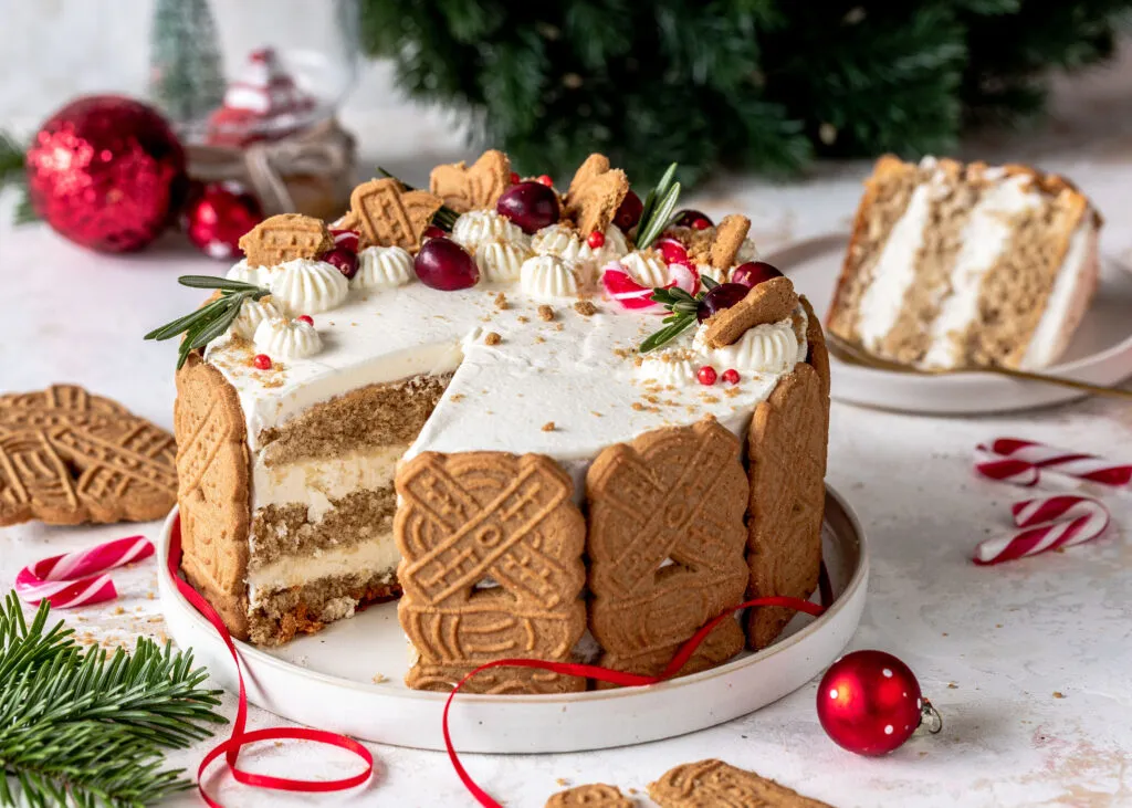 Bratapfel-Spekulatius-Torte von oben mit detailreicher Dekoration aus Sahne, Cranberries und Rosmarin, bereit zum Servieren.
