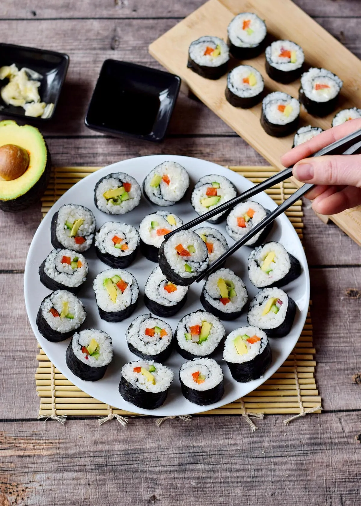 Bunt belegtes veganes Sushi auf einem weißen Teller mit Stäbchen, eine leichte und vielseitige Lunch-Idee für Freunde und Familie.