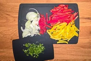 Bunte Paprikaschoten, Zwiebeln und Peperoni werden für das Fajitas Rezept frisch geschnitten und vorbereitet