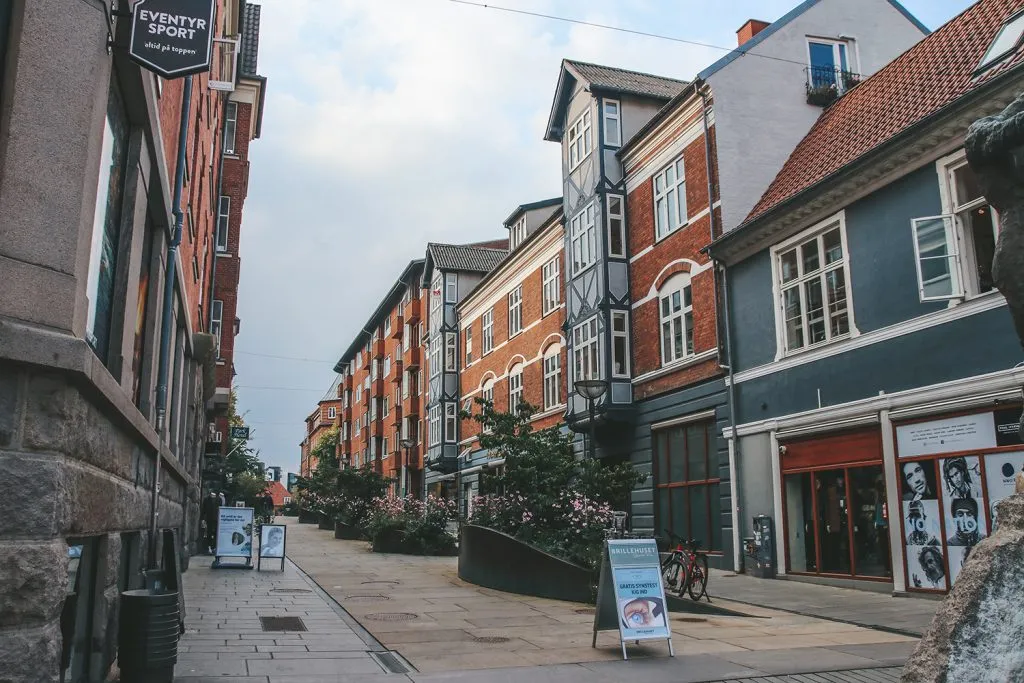 Bunte Regenschirme hängen über einer Fußgängerzone in Vejle und spenden Schatten