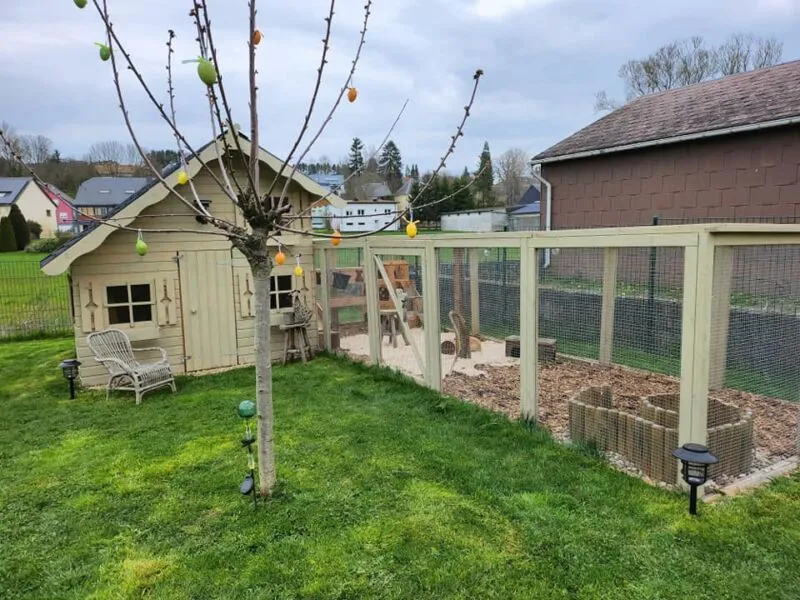Buntes, ansprechend gestaltetes Kaninchengehege mit Außenauslauf, das den Garten optisch bereichert