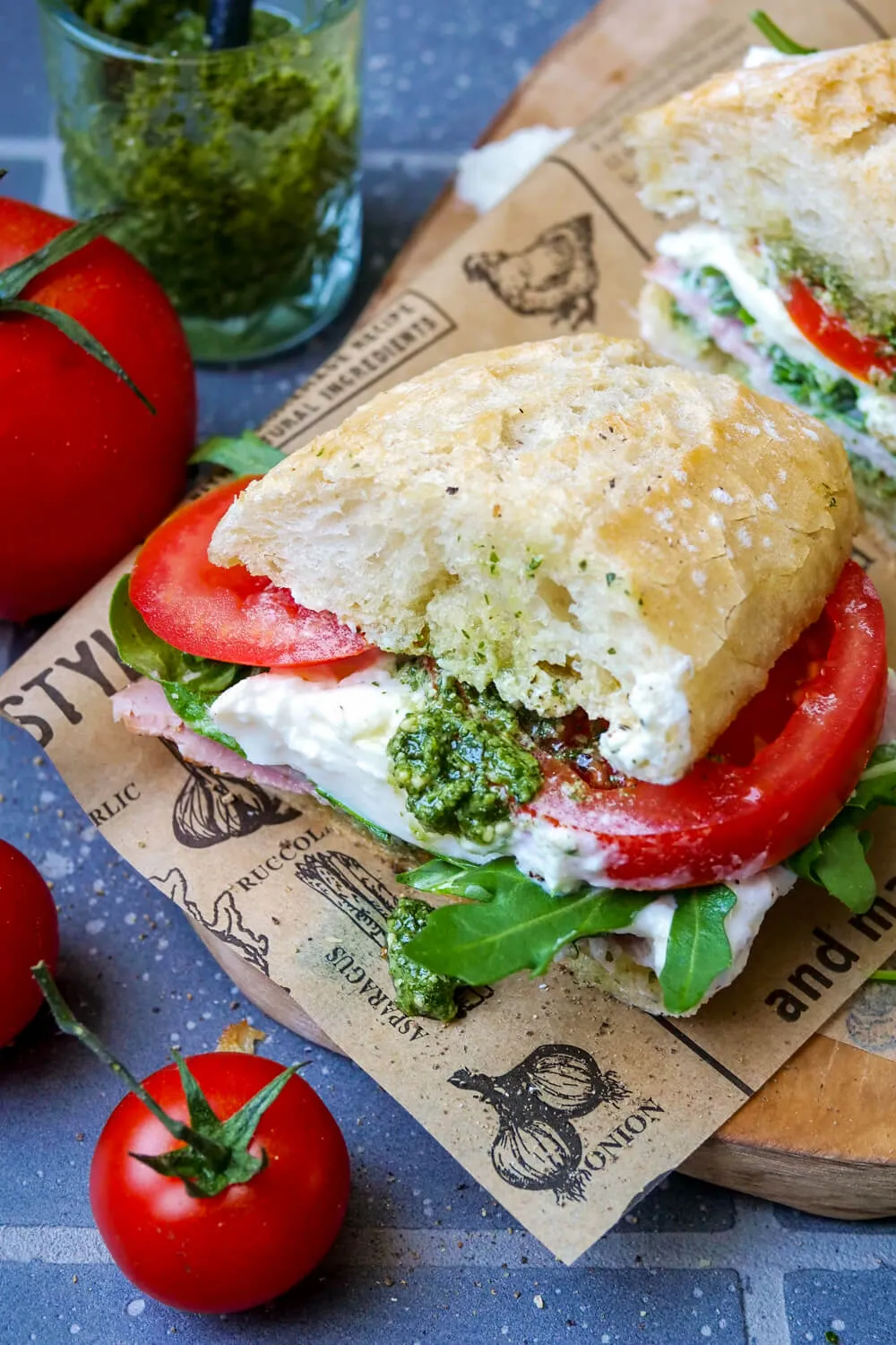 Burrata-Sandwich mit Pesto und Tomaten auf Papier.