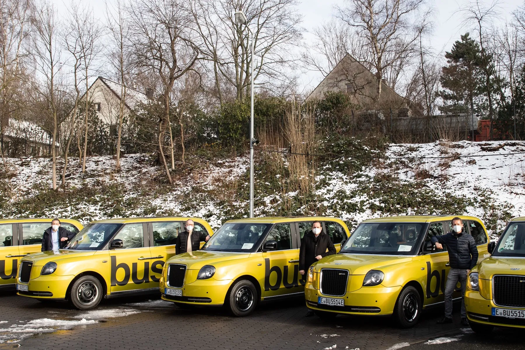 Bussi On-Demand-Service in Essen: Mitarbeiter der Ruhrbahn und Via vor den neuen goldgelben London Taxis