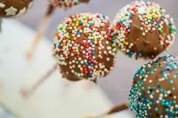 Cake-Pops mit Schokoladenkuvertüre überzogen und bunten Streuseln verziert, ein Genuss für Kindergeburtstage.
