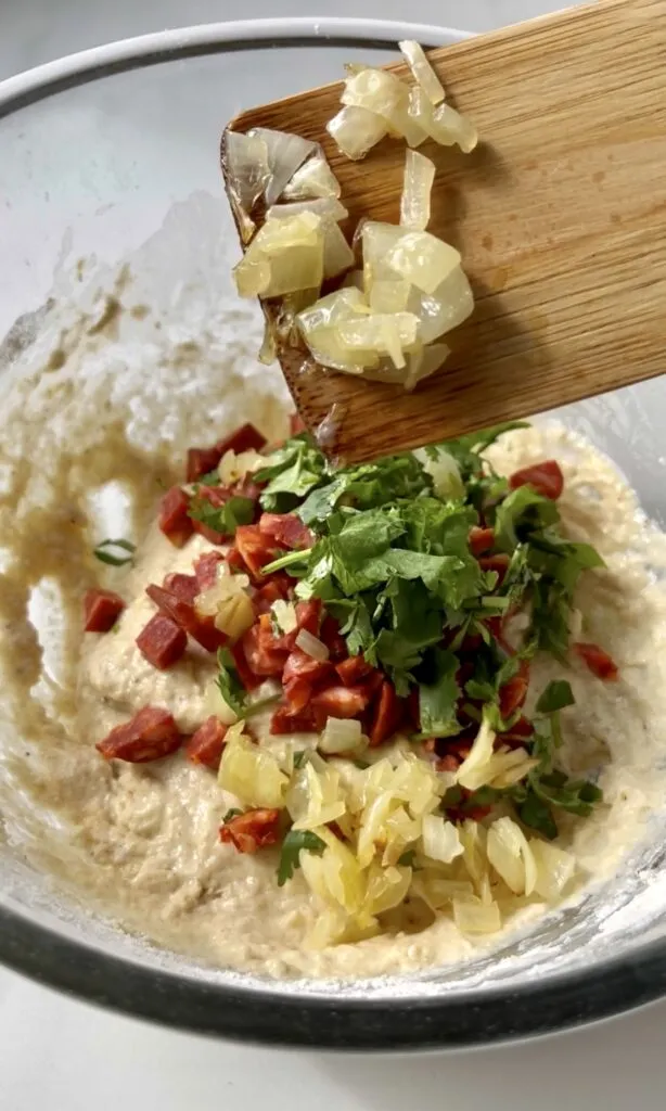 Capuns-Teigfüllung in einer großen Schüssel, vermischt mit gehackter Zwiebel, Salsiz und Petersilie.