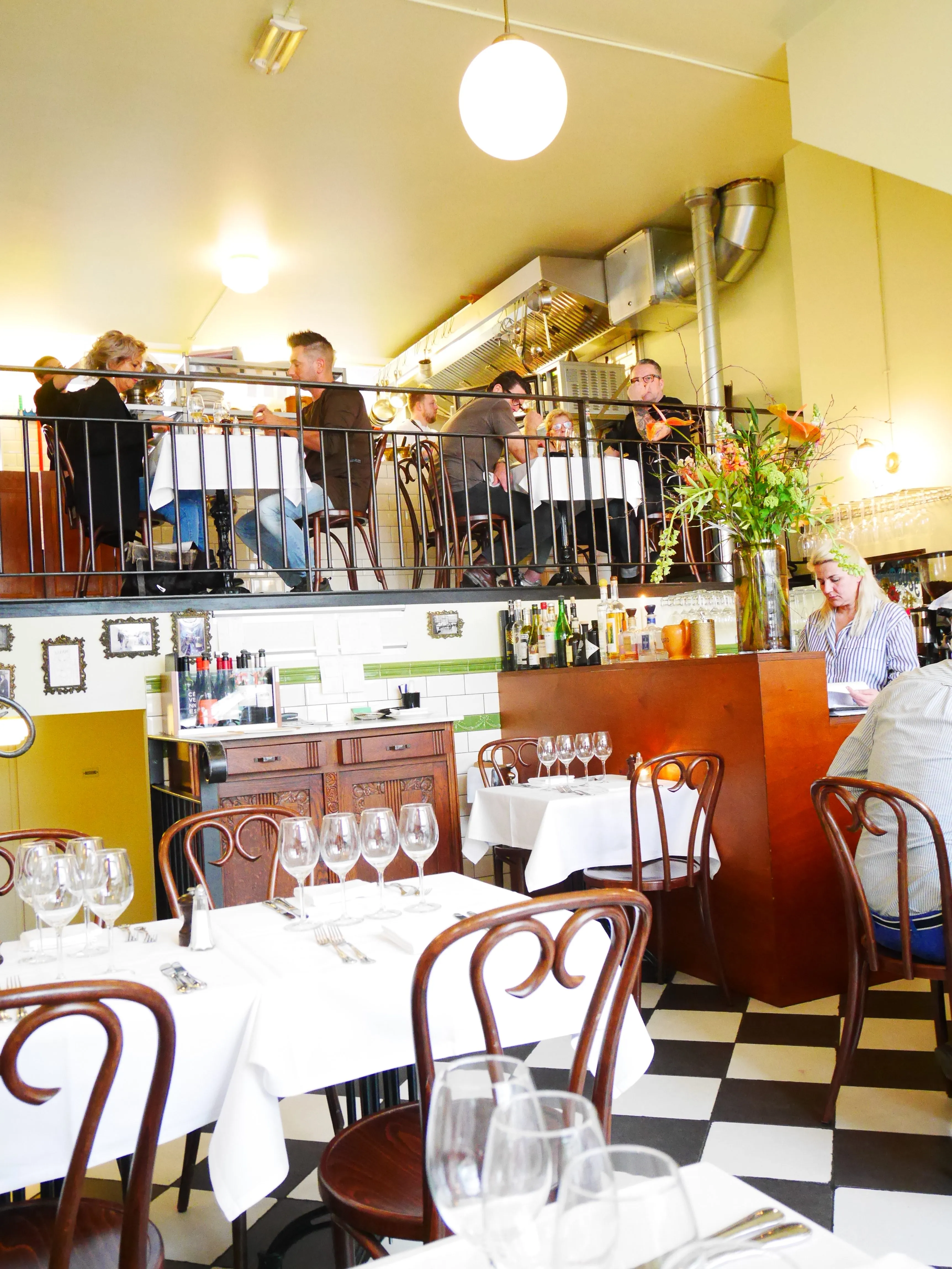 Charmantes, detailreiches Ambiente im Bistrot du Bac mit französischen Postern an der Wand, das zum Verweilen einlädt.